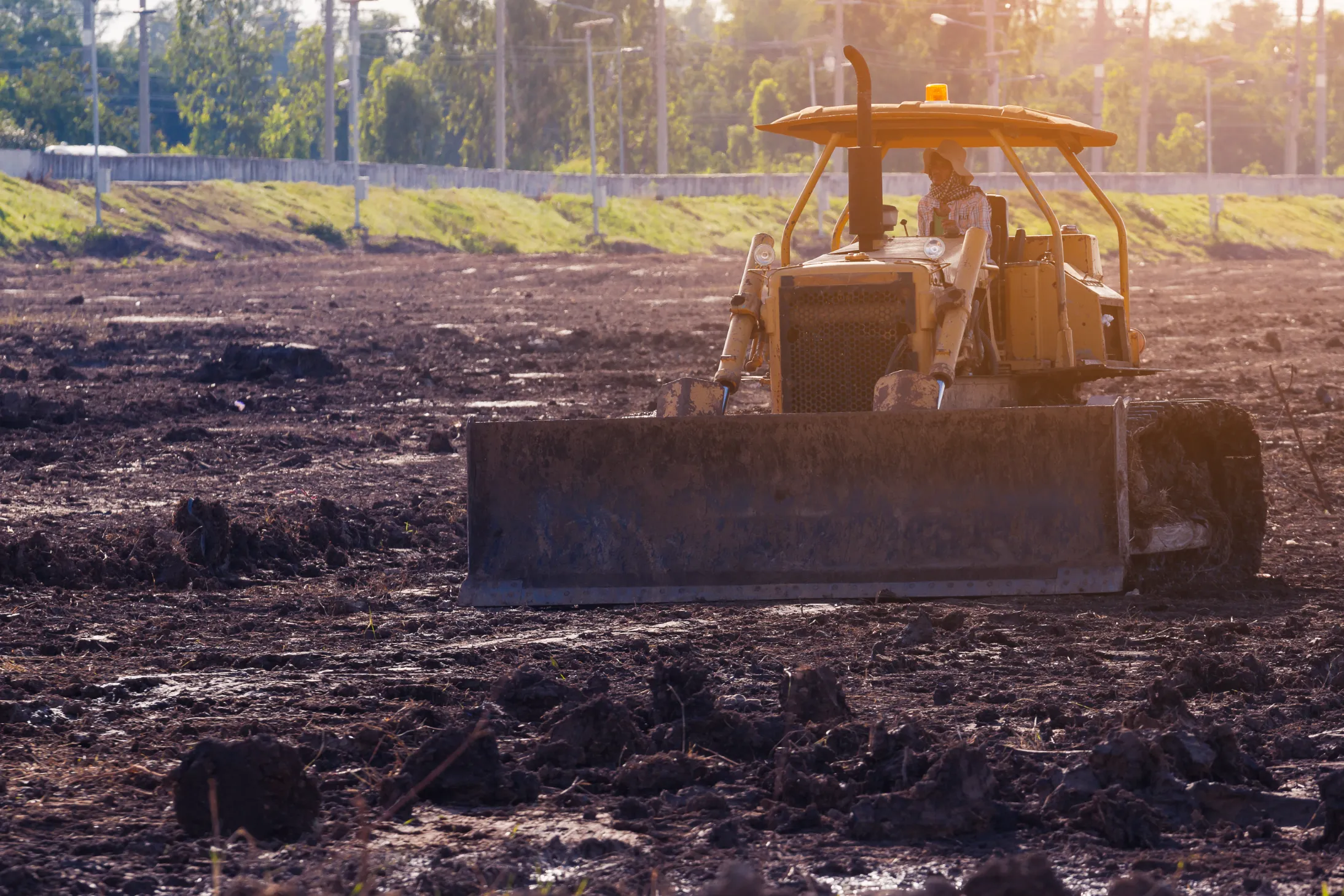Yellow bulldozer moving earth and grading soil on a rural construction site.