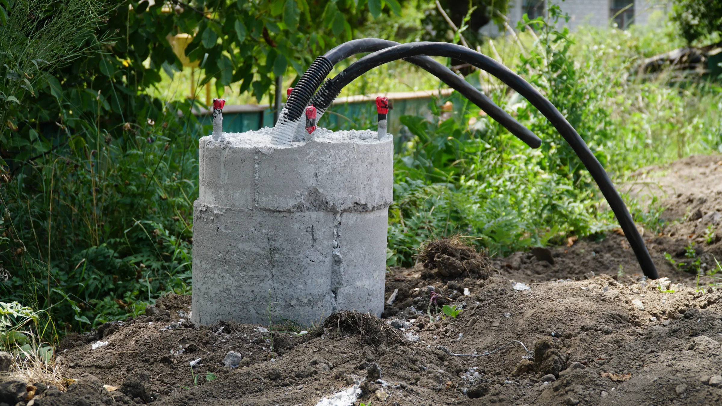 Prepared concrete foundation base with utility cables set in a lush rural landscape.