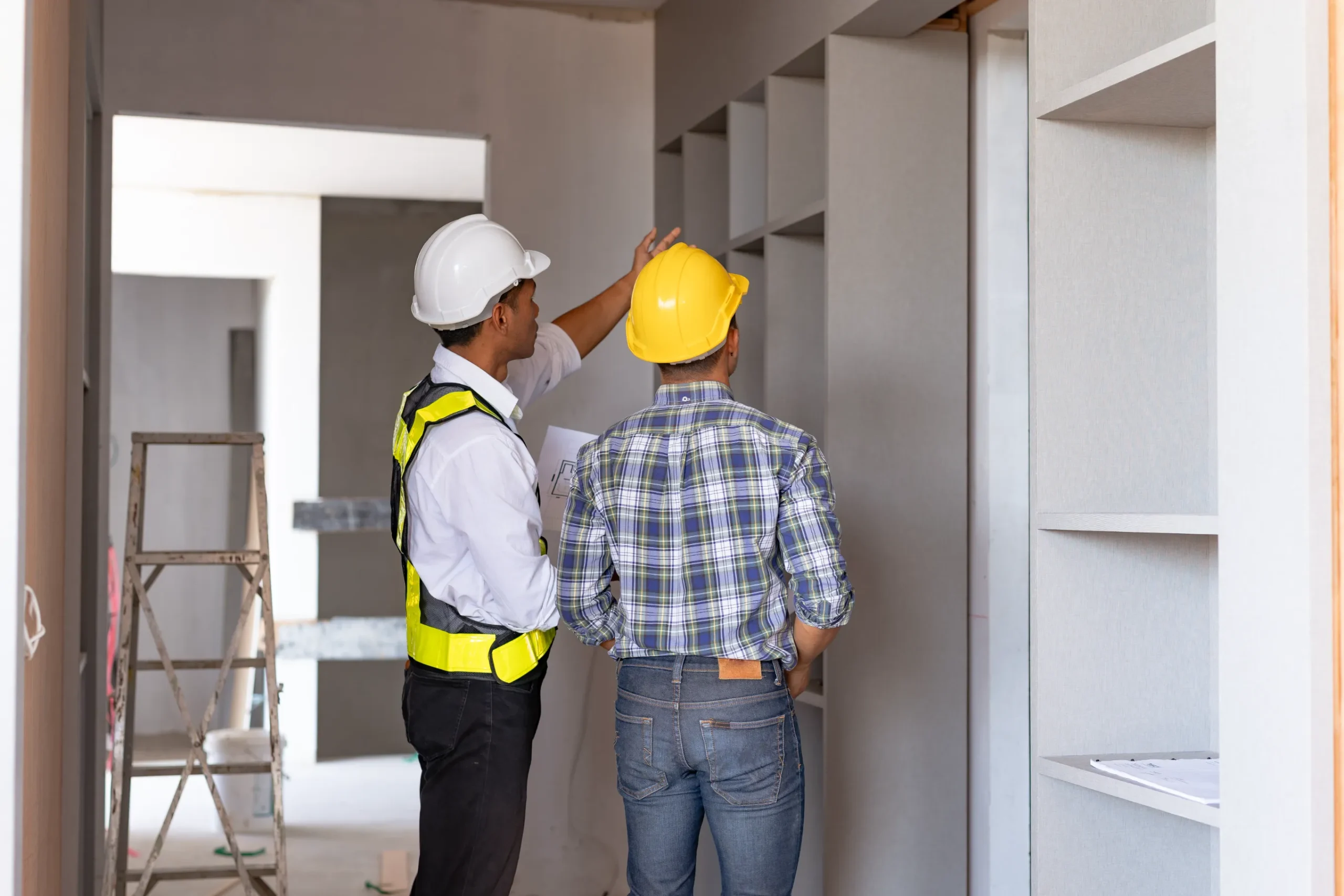 Two construction workers inspecting building blueprints at an active construction site.